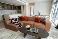 3 Bedroom Condo for Sale at Arom Wongamat living room with terracotta sectional sofa and open kitchen