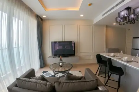 1 Bedroom Condo for Sale at Cetus Beachfront open-plan living room with sofa, TV wall, and breakfast bar seating