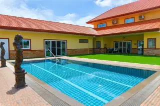 Miami Villas private outdoor pool with bronze statues green lawn and red-roofed yellow villa exterior