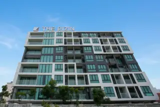 The Rizin Hotel & Residences: Modern condominium exterior with white and dark grey facade, many balconies, and large windows.