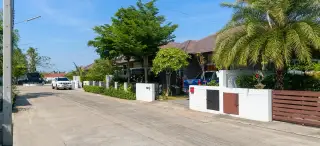 Baan Panalee modern single-story house exterior with dark grey walls, a covered porch, and green lawn.