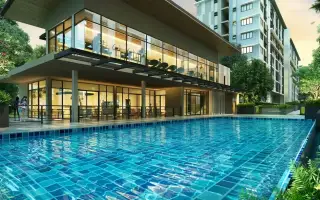 G Condo Sriracha clubhouse with glass-walled lounge and fitness area beside tiled swimming pool