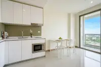 1 Bedroom Condo for Sale at The Riviera Jomtien modern kitchen with white cabinets, appliances, and dining table.