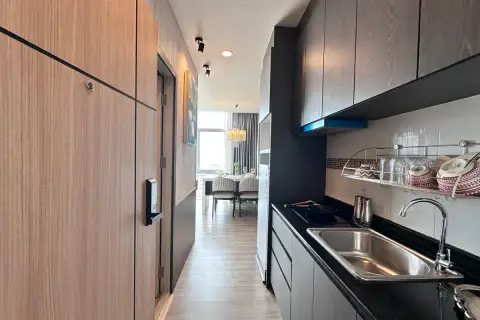 1 Bedroom Condo for Sale at The Twin Tower Jomtien Beach Pattaya narrow kitchen with dark cabinets, black countertop, and view to dining area