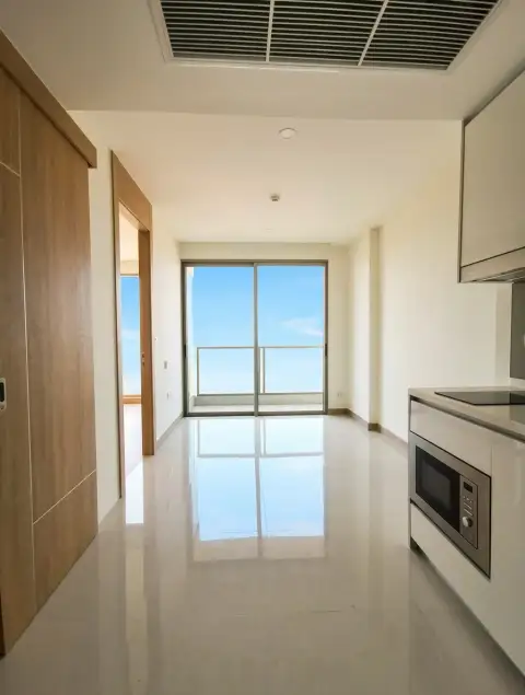 1 Bedroom Condo for Sale at The Riviera Jomtien open living area with kitchen and balcony sliding doors