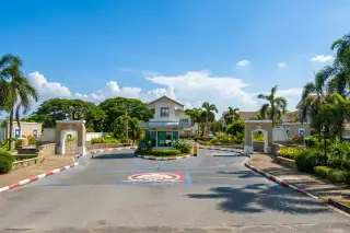 Baan Fah Rim Haad large swimming pool with poolside lounge chairs, palm trees, and a clubhouse building.