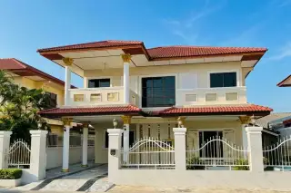 Eakmongkol 3 single-story house with red tiled roof, white facade, and black wrought iron fence.