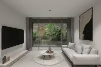 2 Bedroom Condo for Sale at Celine Wongamat bright living room with grey sofa, round coffee table, and garden view through floor-to-ceiling glass doors