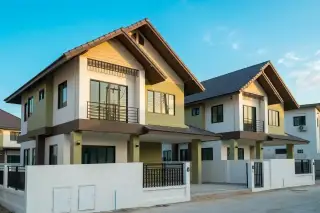 Baan Somthawin 2: Row of modern two-story houses with white and light green facades, dark roofs, and balconies.