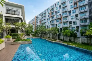 Dormy Residences Sriracha condo building exterior with tiled outdoor swimming pool and tropical landscaping