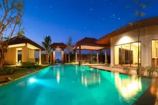 Baan Balina 4: Luxury villa with illuminated swimming pool and traditional Thai-style buildings at night under a starry sky.