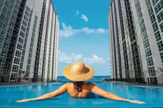 The Twin Tower Jomtien Beach Pattaya woman in straw hat relaxing in rooftop infinity pool with sea view between twin towers