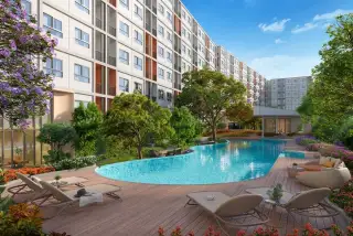 Dcondo Vale Sriracha curved swimming pool with wooden deck, loungers, and lush garden landscaping