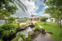 4 Bedroom House for Sale in Nong Prue with a lush green garden, decorative pond, and the house in the background.
