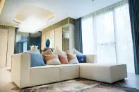 3 Bedroom Condo for Sale at SKYPARK Lucean Jomtien Pattaya bright living room with white L-shaped sofa, crystal chandelier, and sheer floor-to-ceiling curtains