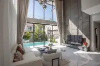 5 Bedroom House for Sale at The Lake Huay Yai bright living room with double-height windows, white sofa, marble floors, and pool view