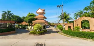 AD House exterior with red tile roof, covered carport with red truck, and white perimeter wall.