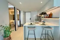 1 Bedroom Condo for Sale at Celine Wongamat: Kitchen island with bar stools, and a view into the modern bathroom.