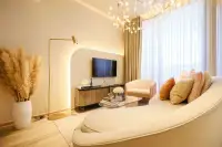 1 Bedroom Condo for Sale at Arom Jomtien living room with curved cream sofa, backlit TV niche, and floor-to-ceiling curtains