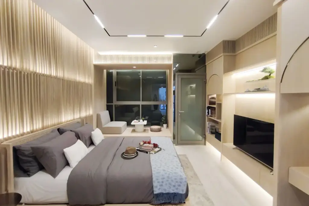 Studio Condo for Sale at SKYPARK Lucean Jomtien Pattaya: Modern studio bedroom with bed, seating area, and TV unit.