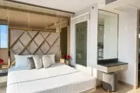 2 Bedroom Condo for Sale at The Riviera Jomtien: Master bedroom with a large bed, decorative headboard, vanity table, and glass-enclosed shower.