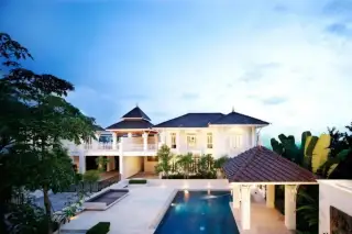 Tadarawadi South Pattaya large white house with pool, outdoor pavilion, and lush greenery under a blue sky.