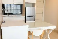1 Bedroom Condo for Sale at Cetus Beachfront white kitchen with island countertop, induction hob, and stainless steel fridge