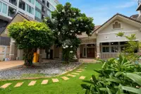 4 Bedroom House for Sale & Rent in Bang Lamung landscaped front garden with plumeria tree, stepping stones, and wooden entrance door