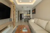 1 Bedroom Condo for Sale at Zensiri Estates and Residences open-plan living room with wood TV unit, beige sofa, and kitchen beyond