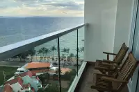 1 Bedroom Condo for Sale at Cetus Beachfront balcony with glass railing, two wooden chairs, and panoramic sea view at dusk