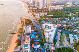 Whale Marina aerial view showing the condo, river, beach, and distant Pattaya city skyline.