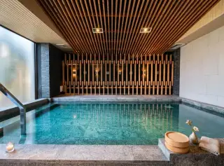 Stasia Dormy Residence indoor onsen-style pool with wooden slat wall and stone flooring