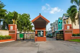 Paradise Hill 2 community entrance gate with guard house and red pillars under a clear sky.