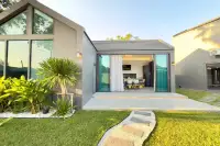 4 Bedroom House for Sale at The Hamlet Pattaya, modern house exterior with sliding glass doors opening to a garden path.
