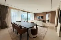3 Bedroom Condo for Rent at Panora Estuaria spacious open-plan dining and living area with dark 8-seat dining table and panoramic city views