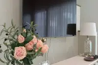 3 Bedroom House for Rent at Supalai Ville Pattaya - Motorway bedroom wall-mounted TV with pink roses and bedside lamp