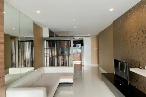 3 Bedroom Condo for Sale at Apus spacious living room with white L-shaped sofa, TV unit, and gold floral accent wall