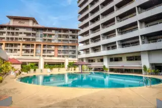 PKCP Tower outdoor swimming pool with surrounding buildings, lounge chairs, and a central umbrella.