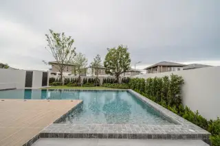 Horizon By Patta modern house with a private pool, a large white 'Horizon' sphere in the water, and a green lawn.