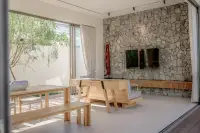 4 Bedroom House for Sale at Dhewee Resort living room with stone feature wall, wooden furniture, and large glass doors.
