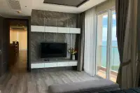 3 Bedroom Condo for Sale at Cetus Beachfront living area with marble feature wall, flat-screen TV, and balcony sea view