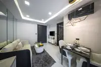 1 Bedroom Condo for Sale at Grand Solaire Noble: Living room with white sofa, coffee table, TV unit, and dining area.