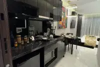Studio Condo for Sale at Grand Solaire Noble kitchen with black marble countertop, built-in appliances, and dining area leading to sleeping area