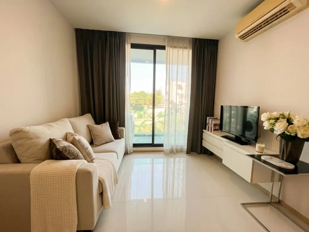 1 Bedroom Condo for Sale at Acqua Condo living room with beige sofa, TV console, and balcony view