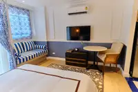 Studio Condo for Sale at Seven Seas Cote d'Azur: Bedroom with bed, sofa, TV, small dining table, and air conditioning unit.