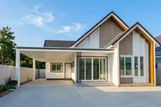 Coco Ville 2 Pong - Bang Lamung - Modern house exterior with white walls, dark roof, and vertical wooden slat accents, under construction.