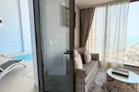 1 Bedroom Condo for Sale & Rent at Copacabana Beach Jomtien: Living room with sofa, glass door leading to a private pool area.