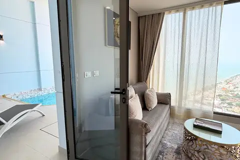 1 Bedroom Condo for Sale & Rent at Copacabana Beach Jomtien: Living room with sofa, glass door leading to a private pool area.
