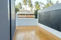 4 Bedroom House for Sale in Pong, outdoor corridor with wooden-look tiles, white walls, and palm trees.