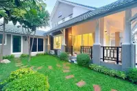 5 Bedroom House for Sale at Central Park 4. Side view of the house with a green lawn, stepping stones, and covered patio.
